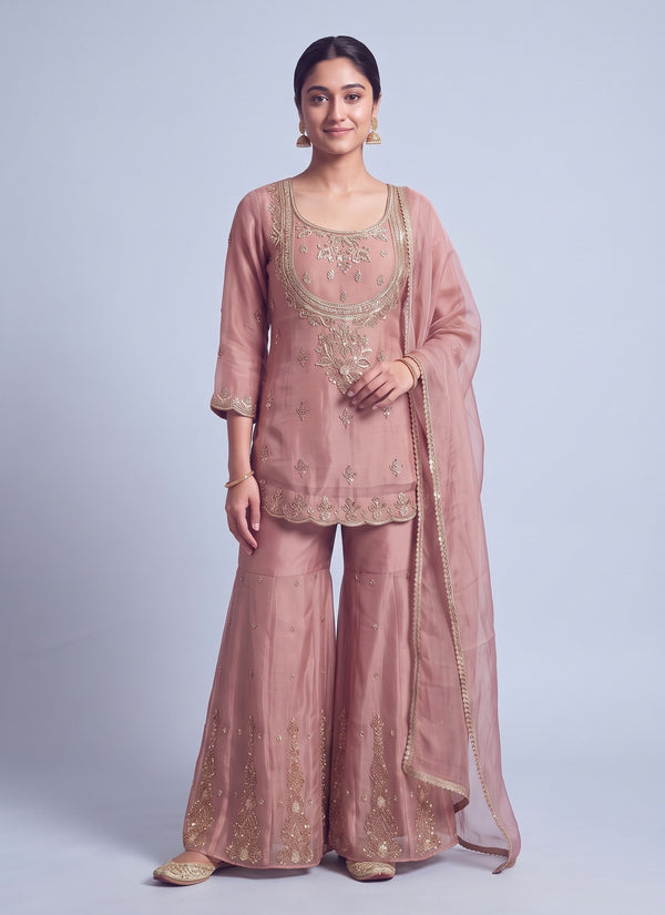 Pink gabana silk sharara set with short kurti, wide scoop neck framed by a gold zari sequin bib and scalloped hem, flared sharara and sheer dupatta, front view