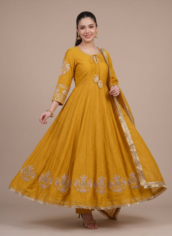 Model twirling in the mustard anarkali gown showing the gold medallion hem and fringe lace