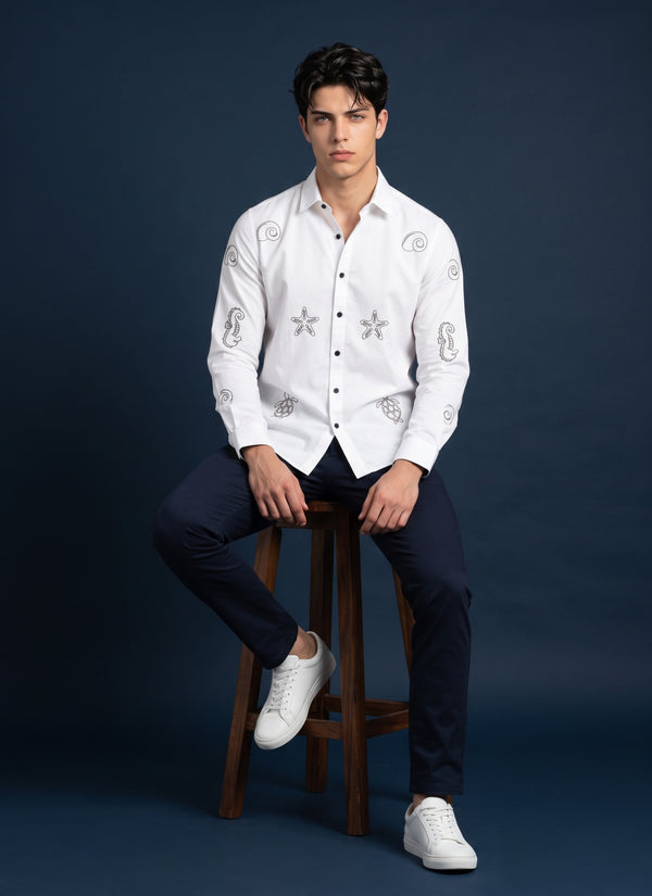 White embroidered shirt for men, seated pose on a wooden stool