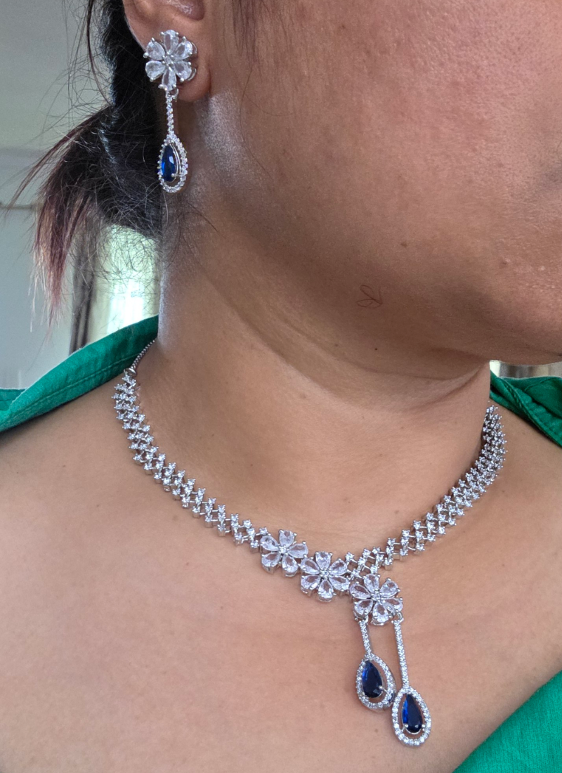 Bridal necklace set with earrings in silver finish, diamond cut stones and striking blue stone centerpiece.